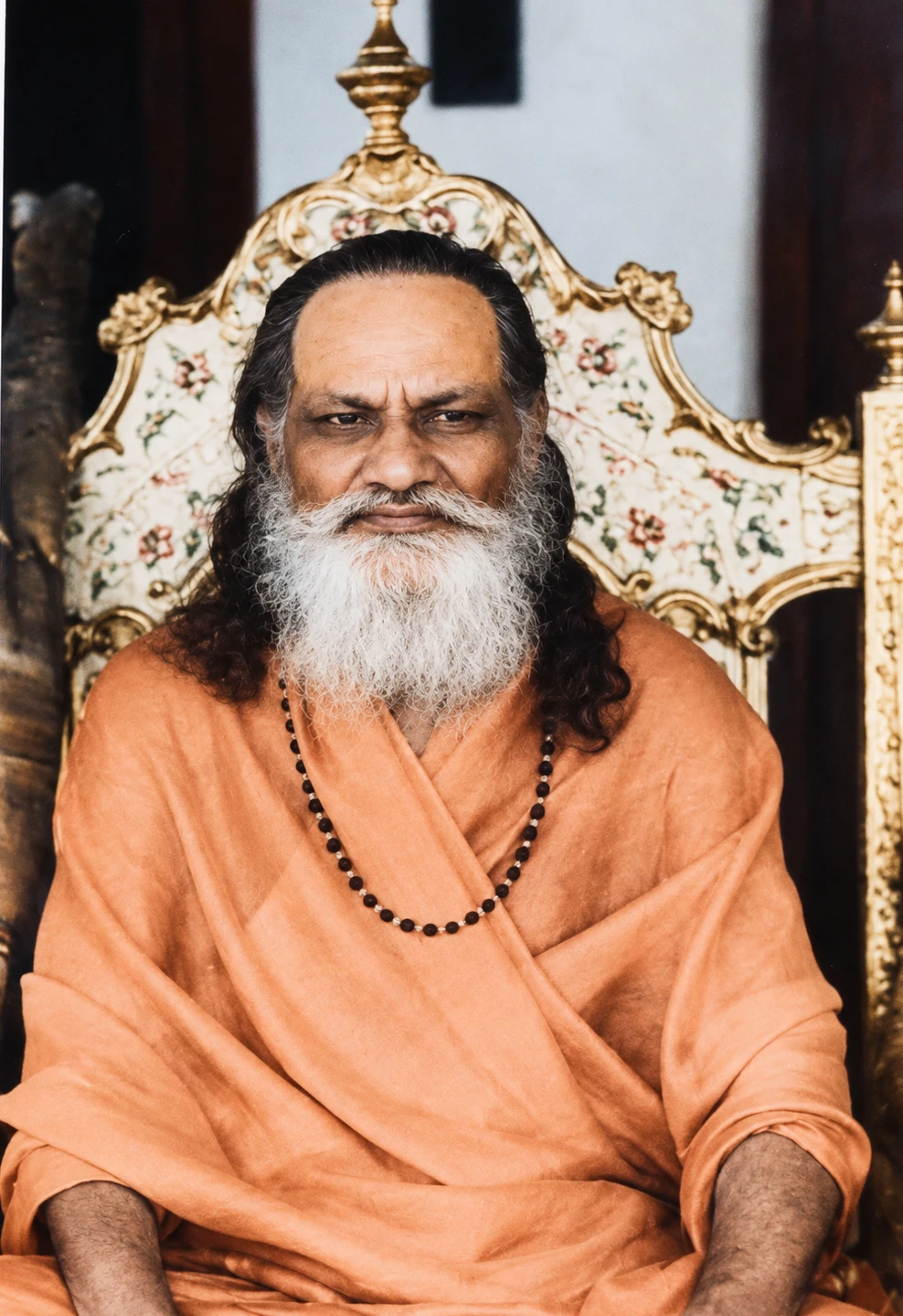 Brahmananda Saraswati seated on an ornate gilded throne, looking toward the camera
